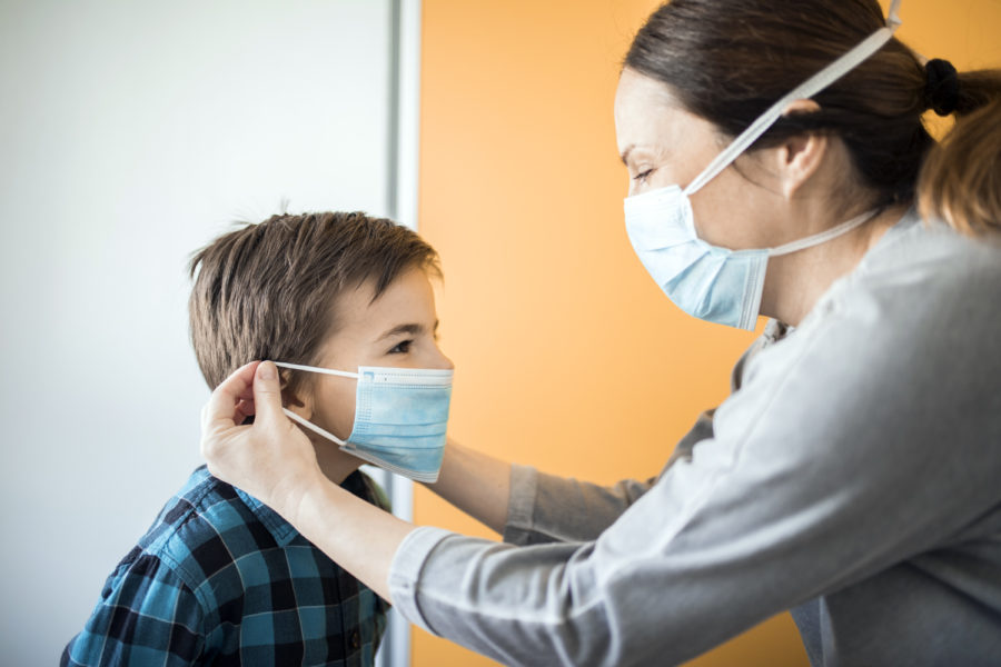 Una madre le pone una mascarilla a su hijo