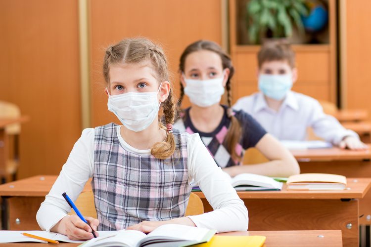 niños con mascarilla estudian ciberseguridad en un colegio