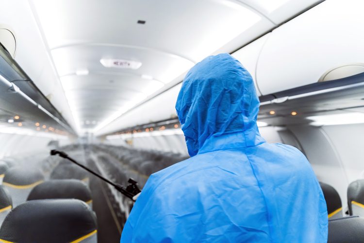 Un operario con un equipo de protección personal (EPP) desinfecta la cabina de un avión comercial