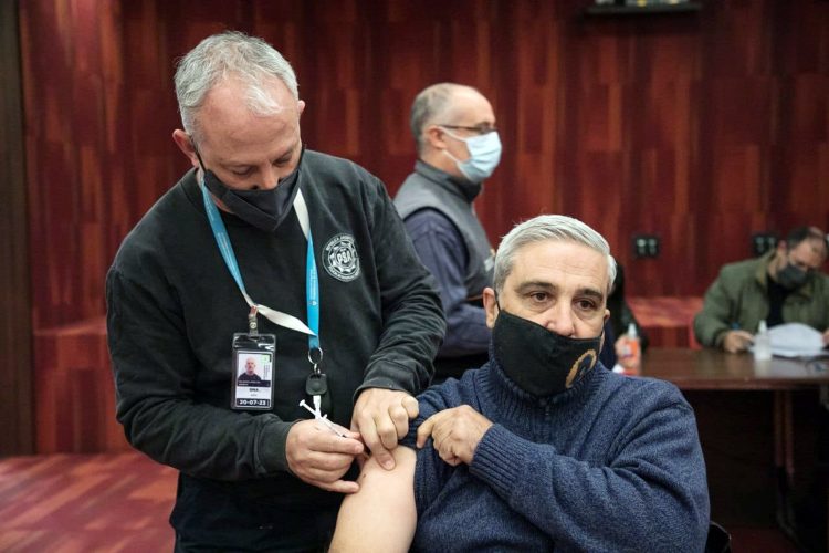 Un miembro de la Policía de Seguridad Aeroportuaria vacuna a un integrante de la Policía Federal Argentina