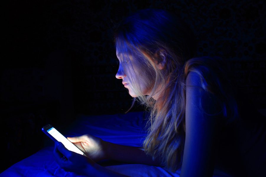 una mujer utiliza su smartphone por la noche en la cama