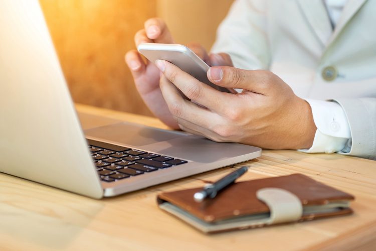 un hombre practica teletrabajo con su ordenador portátil y una agenda