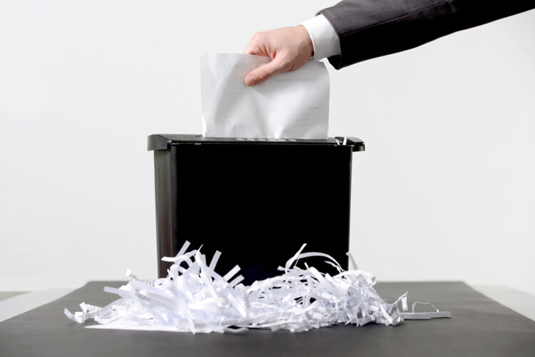 un hombre destruye documentación impresa en una trituradora de papel