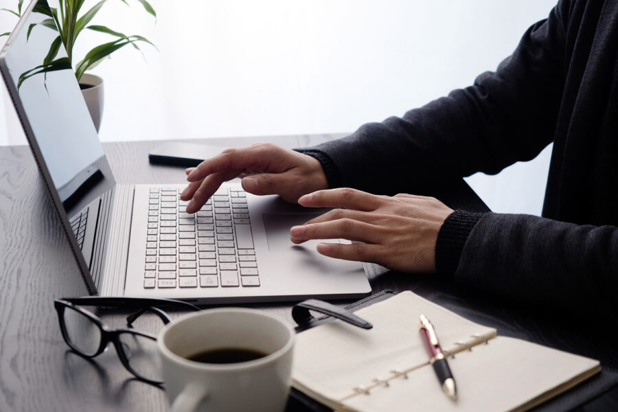 un hombre practica teletrabajo con su ordenador portátil, una agenda y una taza de café