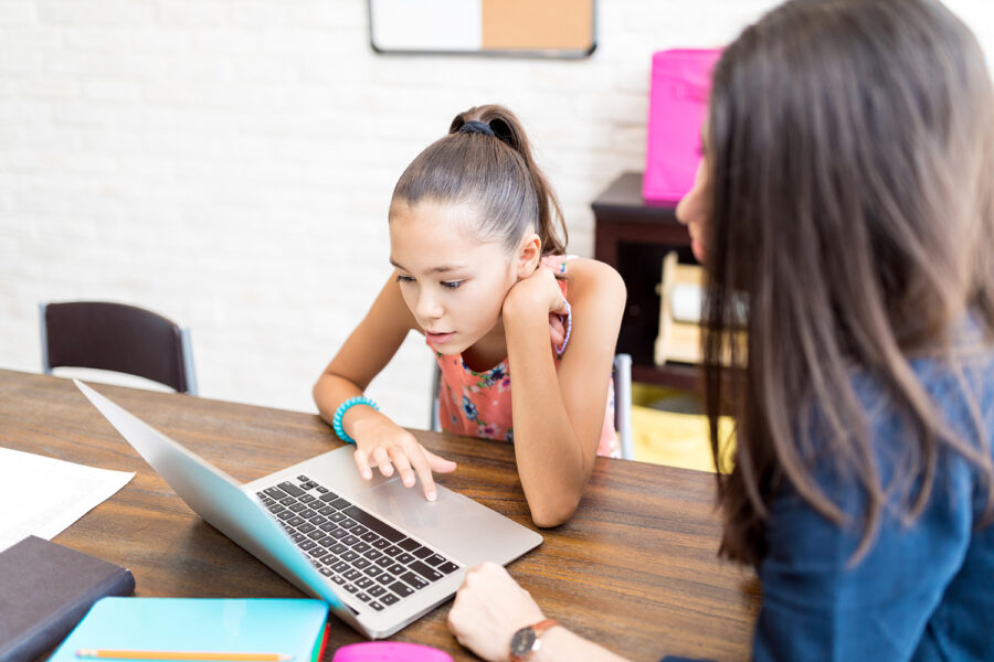 una niña usa un laptop junto a su madre