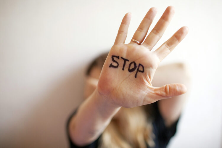 una mujer muestra la palma de su mano con la palabra stop