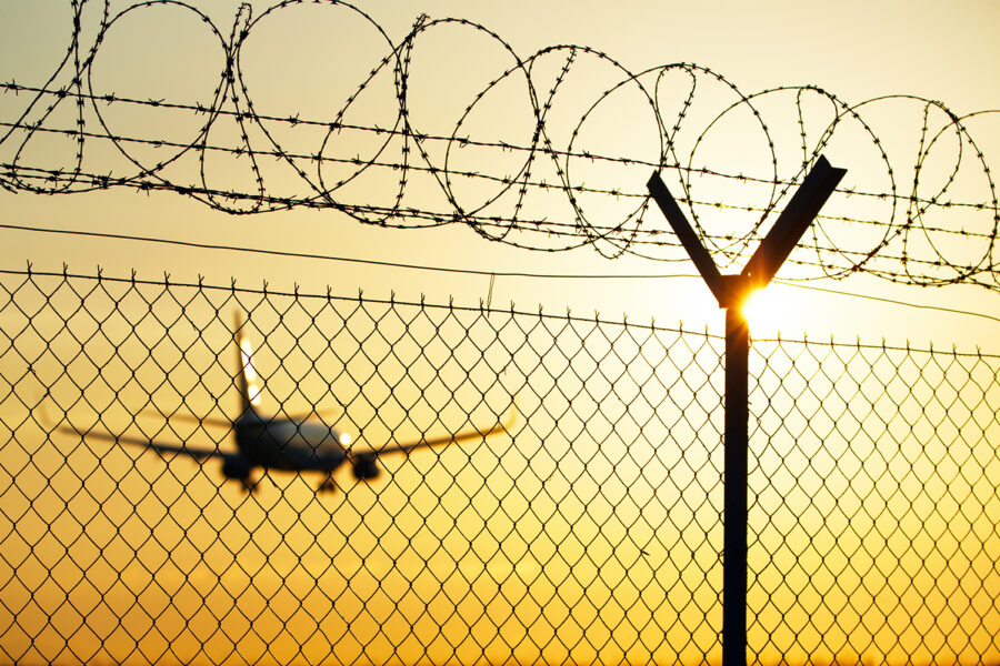 alambrada de protección perimetral de un aeropuerto con un avión al fondo