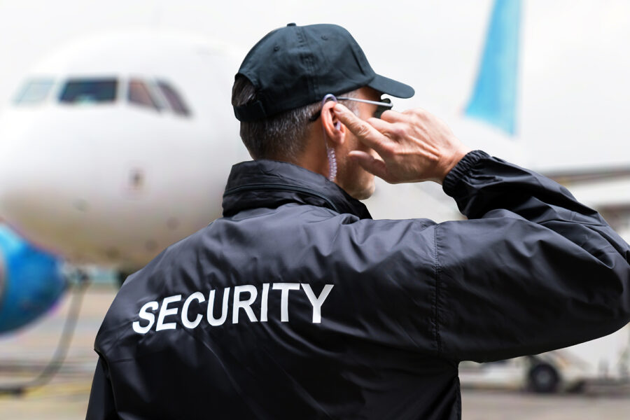 un vigilante de seguridad privada a pie de pista junto a un avión