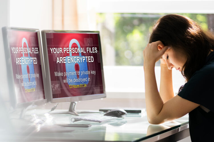 una mujer frente a dos pantallas de ordenador es víctima de un ataque de ransomware