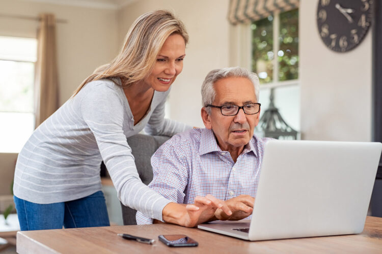 una mujer enseña a un adulto mayor cómo hacer uso de Internet de forma segura