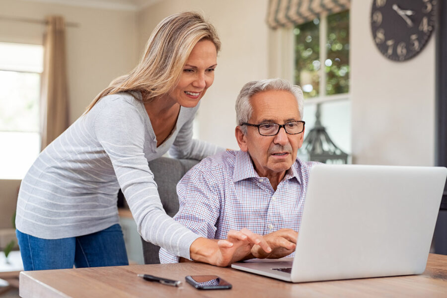 una mujer enseña a un adulto mayor cómo hacer uso de Internet de forma segura