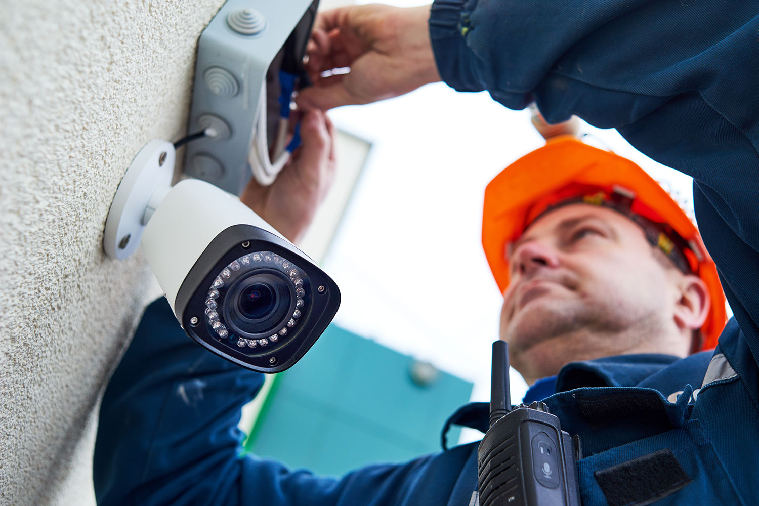 un técnico instala una cámara de videovigilancia en una pared