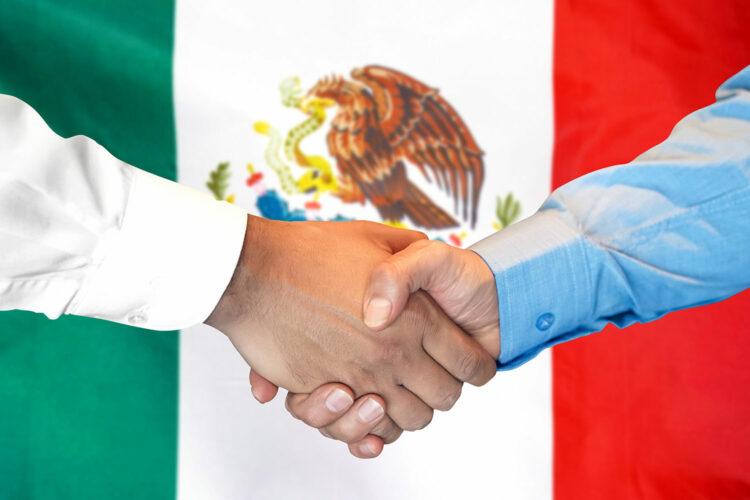 apretón de manos con la bandera de México de fondo