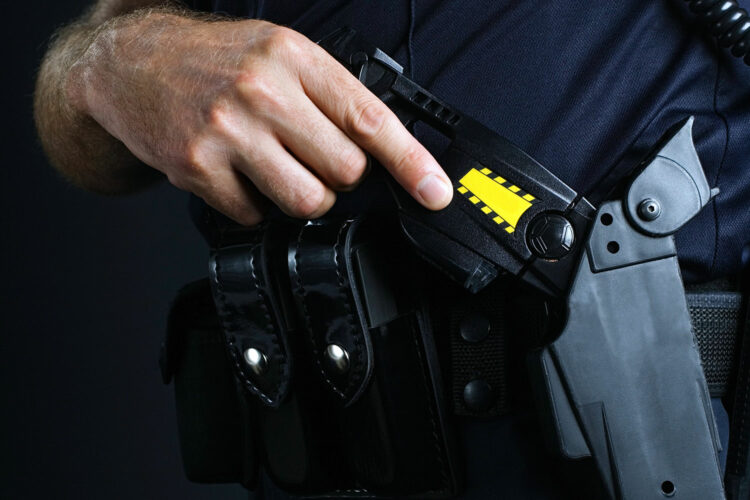 un policía sostiene una pistola taser en su mano