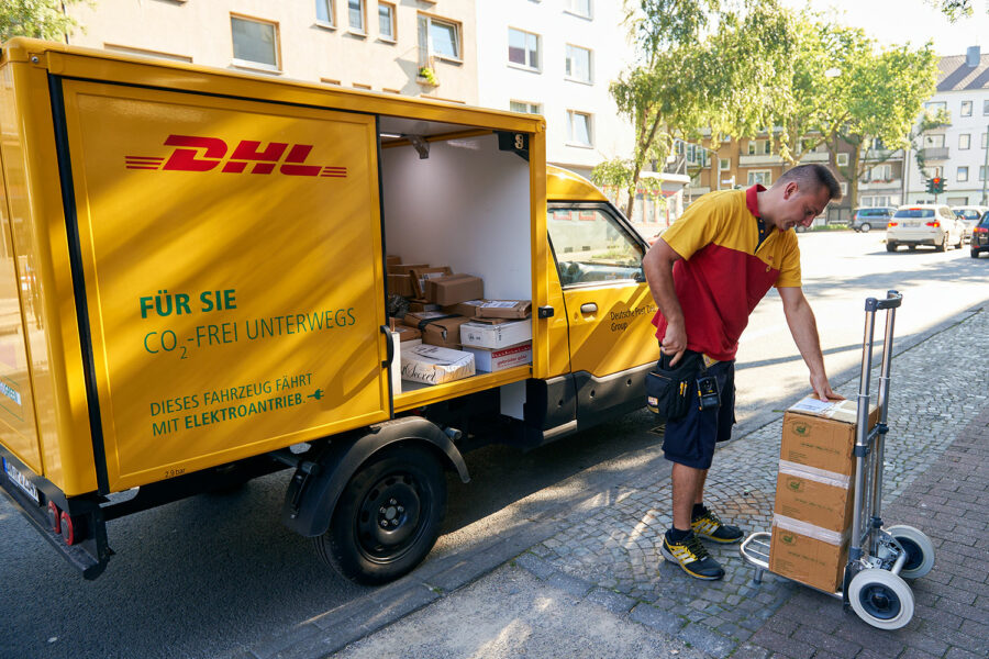 repartidor de DHL junto a su vehículo de reparto