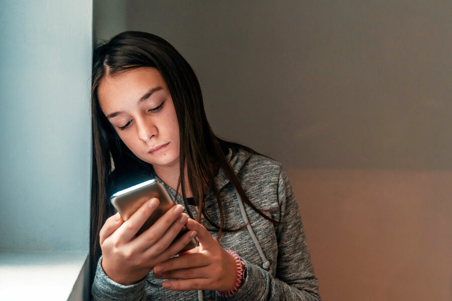 una joven víctima de sextorsión mira su smartphone