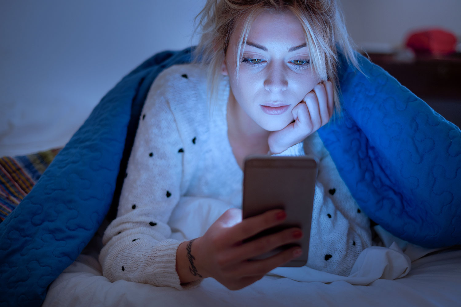 una adolescente mira su smartphone antes de dormir