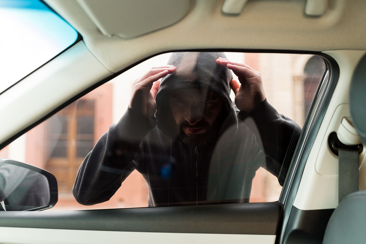 un ladrón observa si hay objetos de valor en el interior de un automóvil