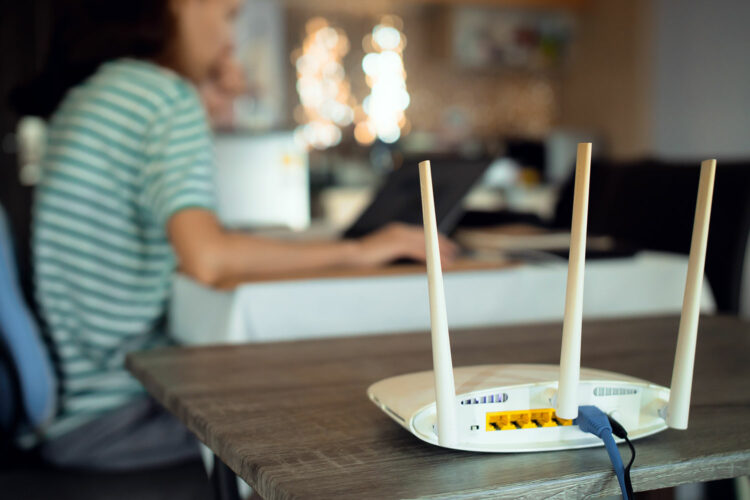 una mujer utiliza un ordenador portátil conectada a un router wifi