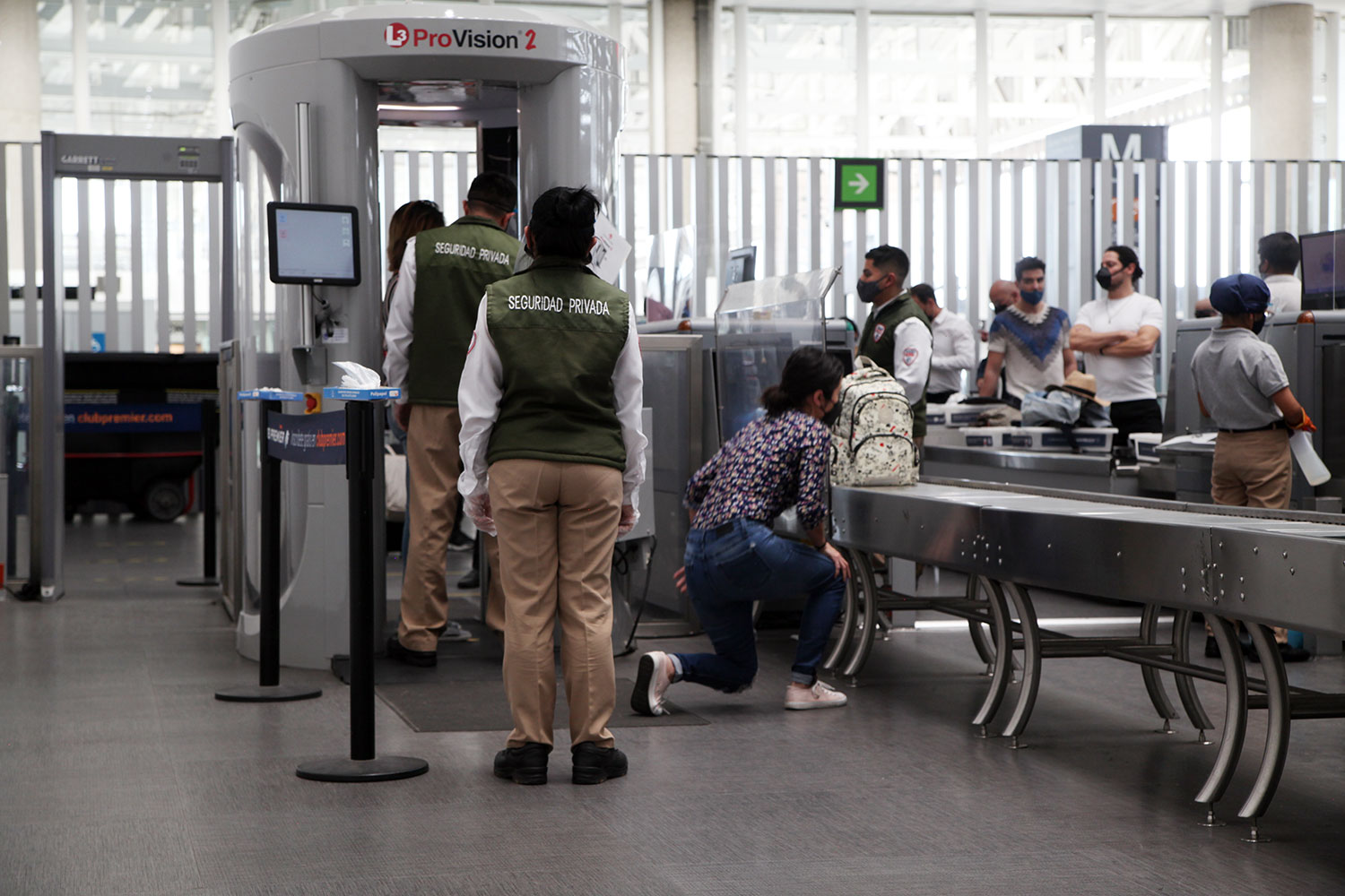 Personal de seguridad privada del Grupo EULEN junto a un escáner para pasajeros en un aeropuerto mexicano