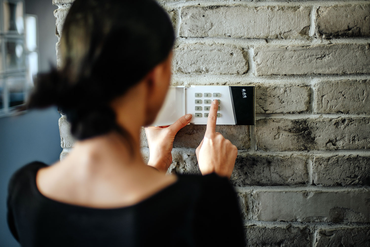 Una mujer introduce el pin de seguridad en el teclado del sistema de alarma de su vivienda