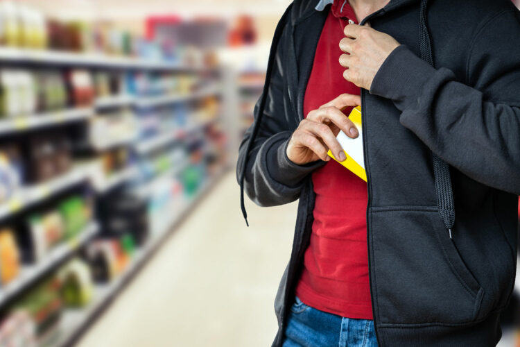 una persona roba un producto en un supermercado