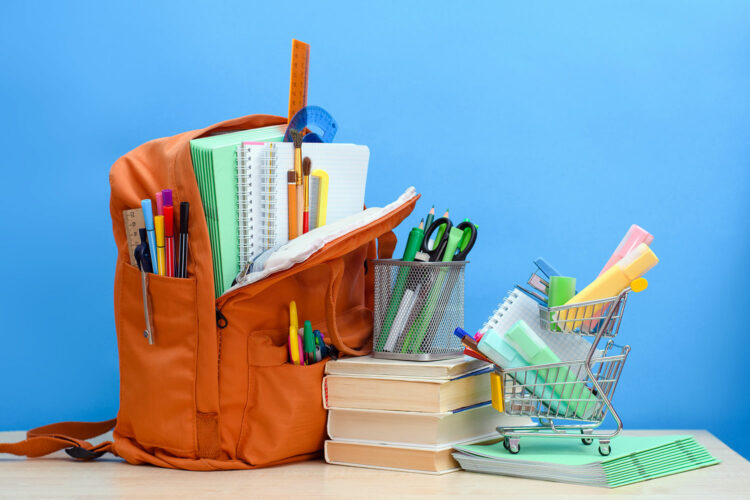 una mochila, libros y material escolar sobre una mesa