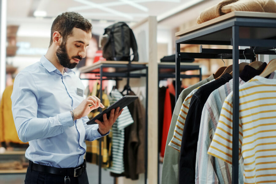 un empleado de una tienda de ropa comprueba el inventario con su tablet