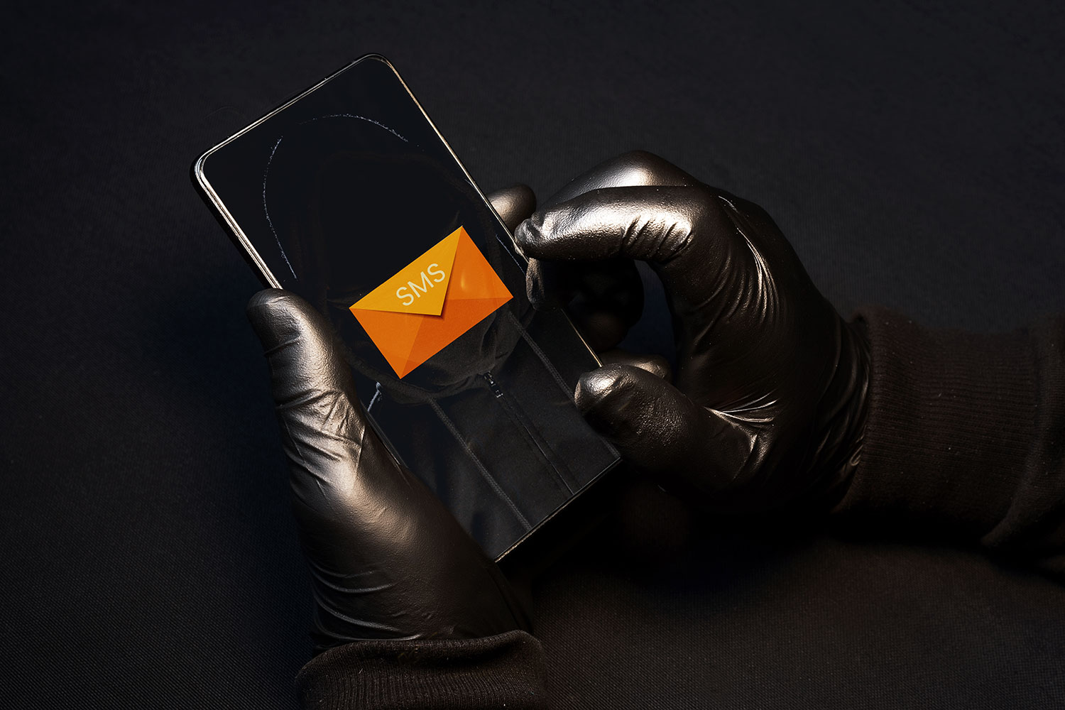 un hacker con guantes practica smishing con un smartphone