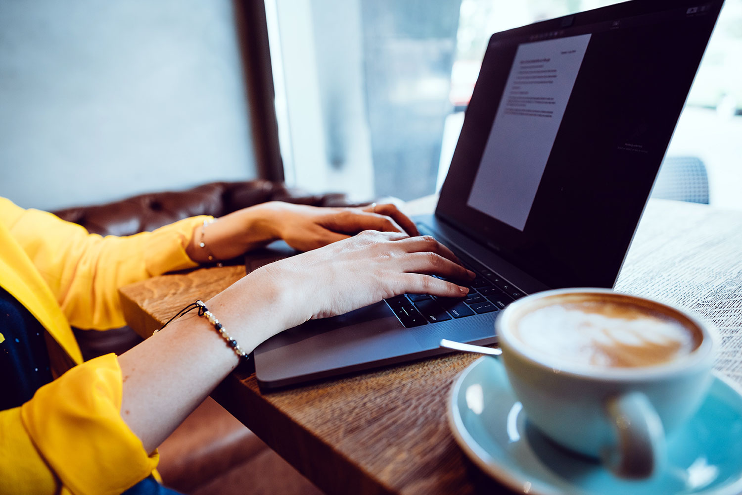 una mujer trabaja con un ordenador portátil junto a un café