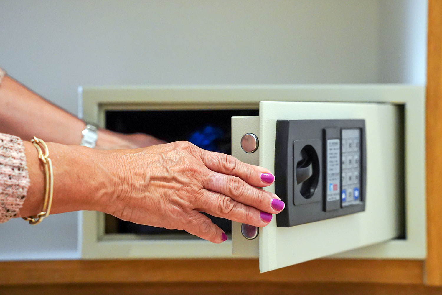 Una mujer deposita objetos de valor en la caja fuerte de la habitación de un hotel