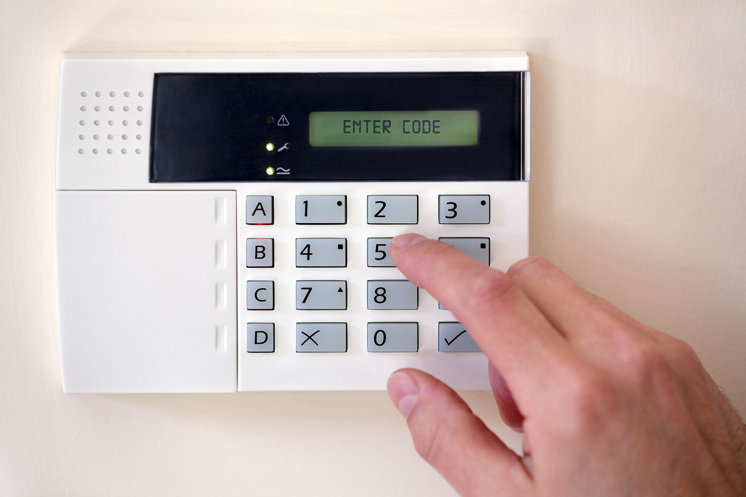 un hombre introduce un código en el panel del sistema de alarma de una vivienda