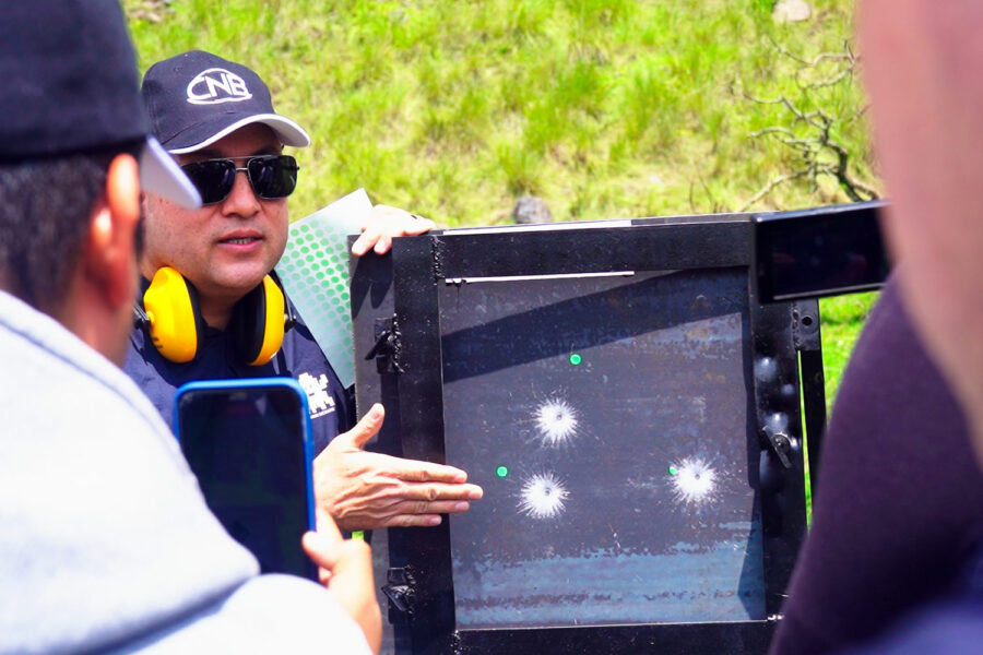 un representante del CNB de México muestra un panel con impactos de bala