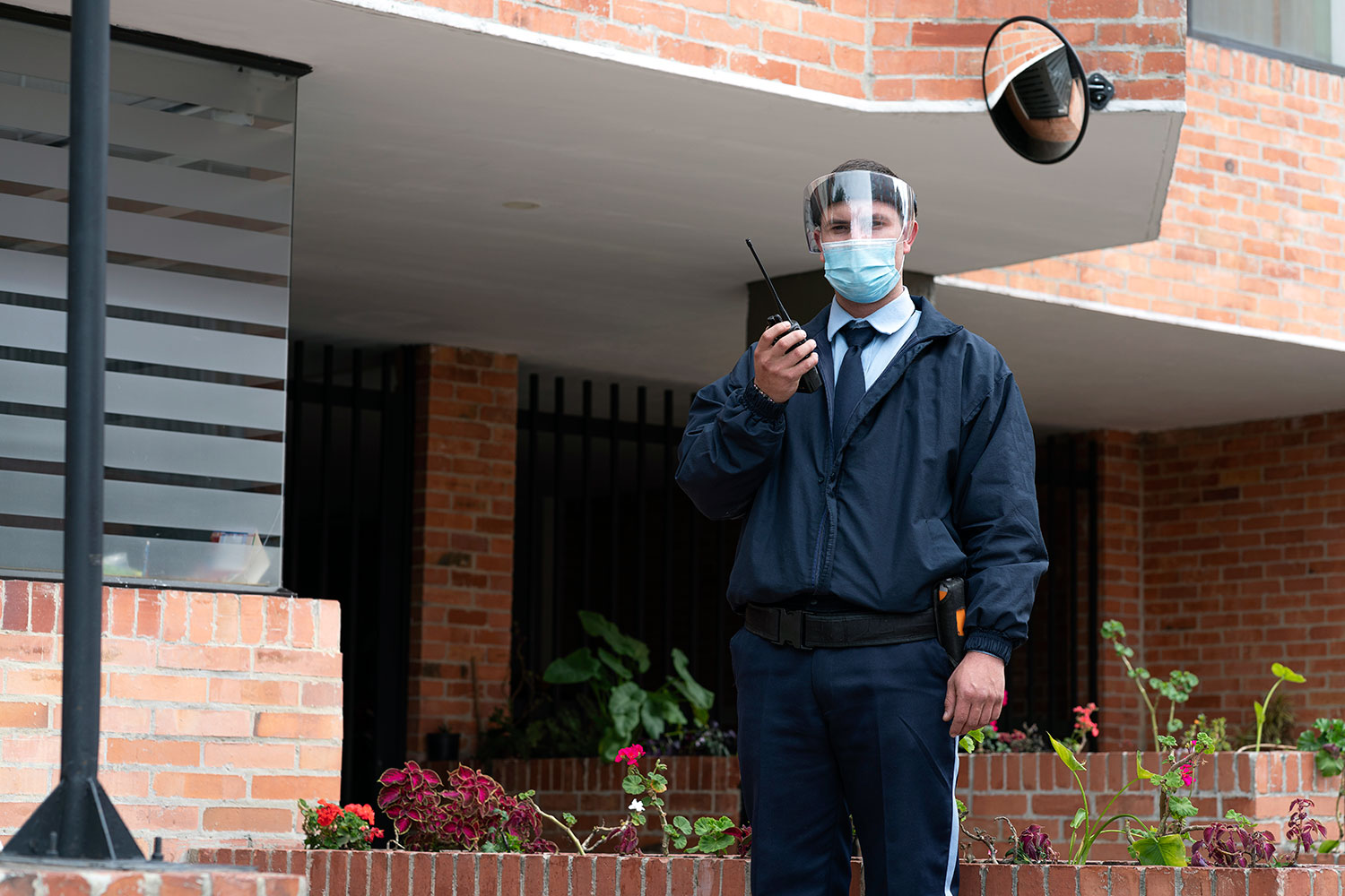 un guarda de seguridad privada con mascarilla presta servicio en un edificio de Bogotá