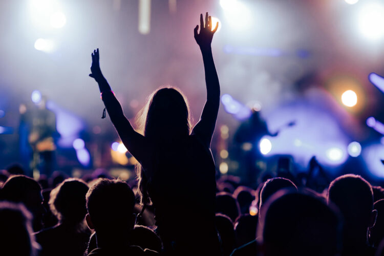 Una mujer del público levanta sus manos en un concierto de rock