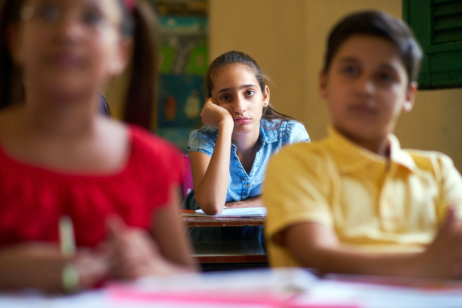 una niña no atiende a las explicaciones del profesor en el aula