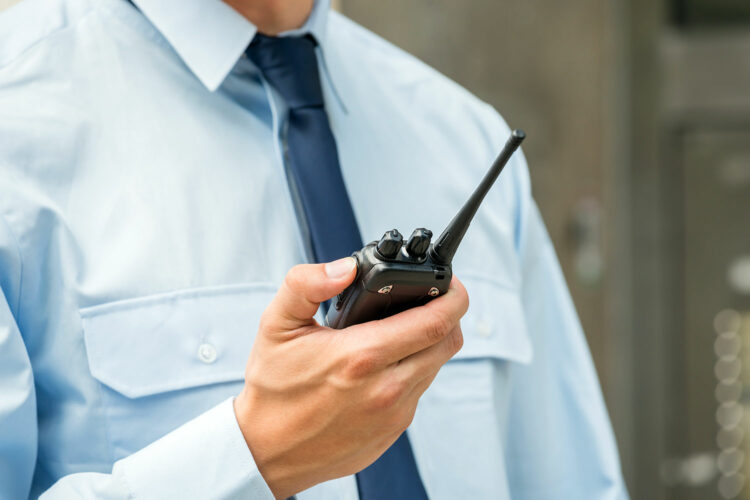 un guardia de seguridad privada sostiene un walkie talkie en la mano