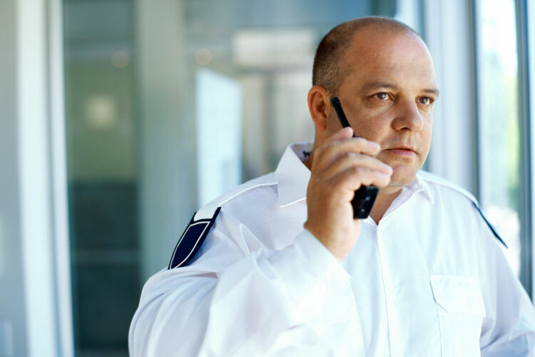 un guardia de seguridad privada habla a través de un walkie talkie