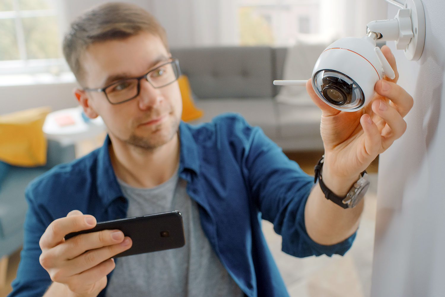 Un hombre instala una cámara de seguridad wifi siguiendo las instrucciones de la aplicación de su móvil