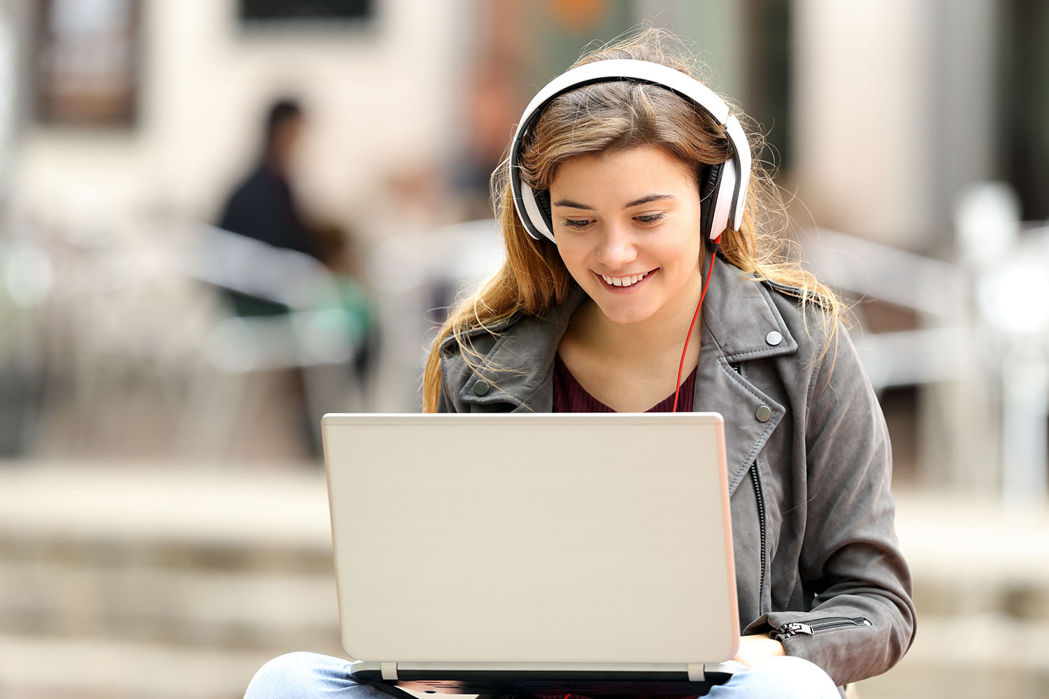 una chica joven utiliza su ordenador portátil con unos auriculares
