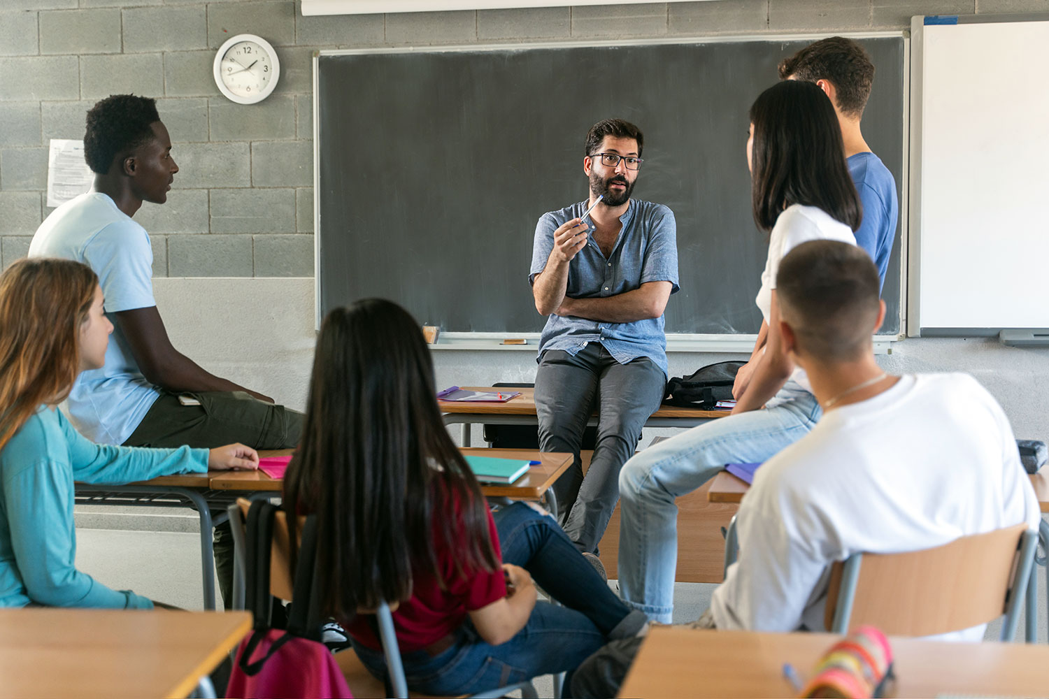 un profesor dialoga con sus alumnos en el aula