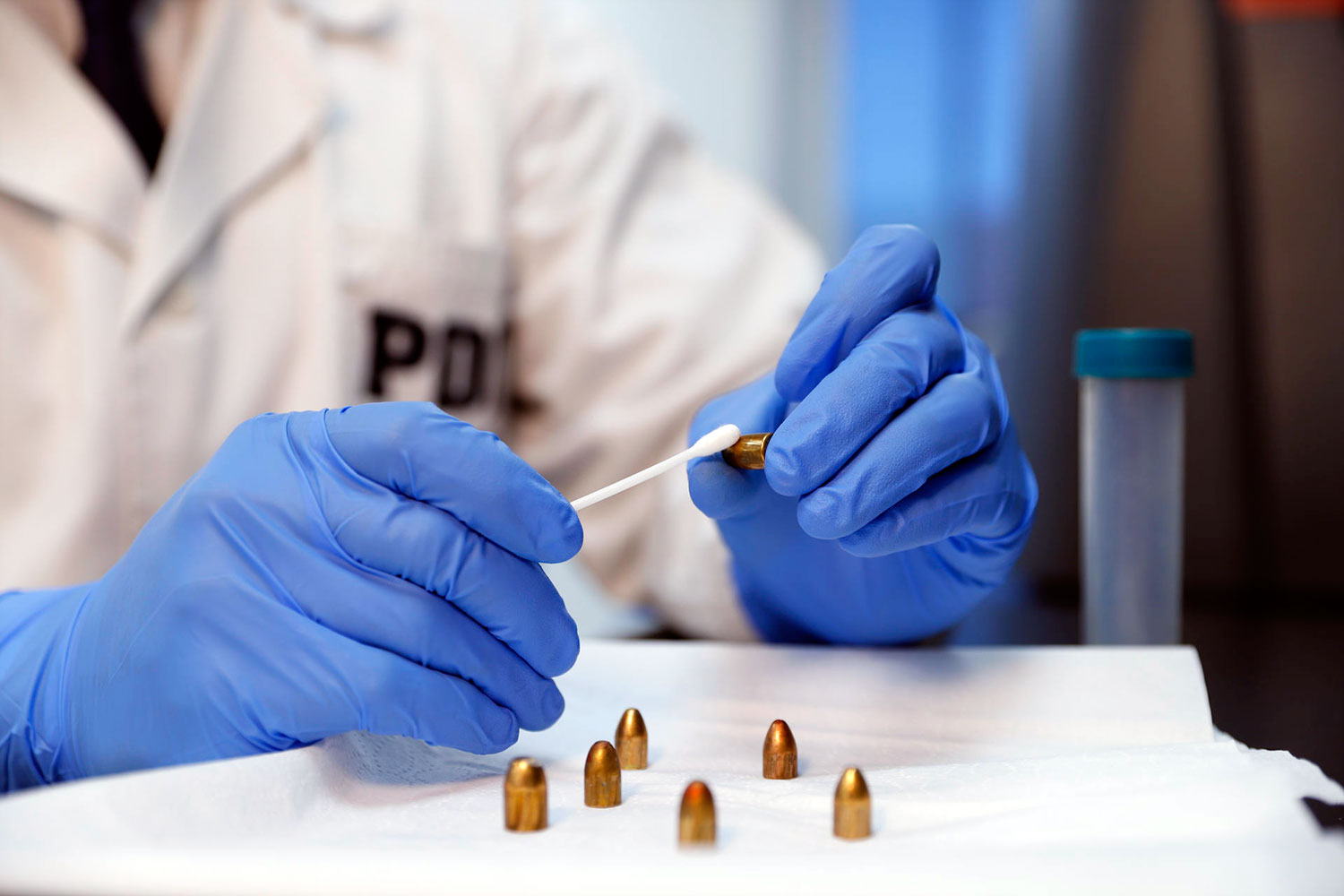 un profesional de un laboratorio de criminalística de la PDI analiza unos proyectiles de arma de fuego