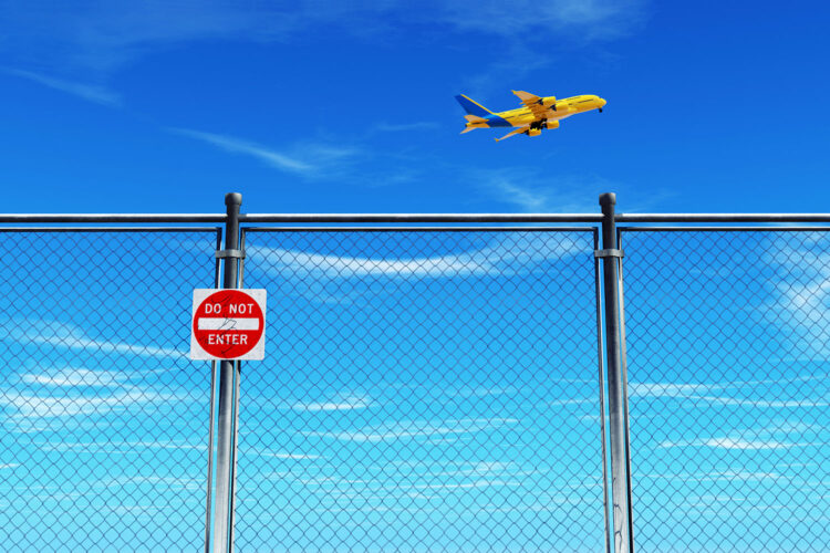 valla perimetral de un aeropuerto y un avión despegando
