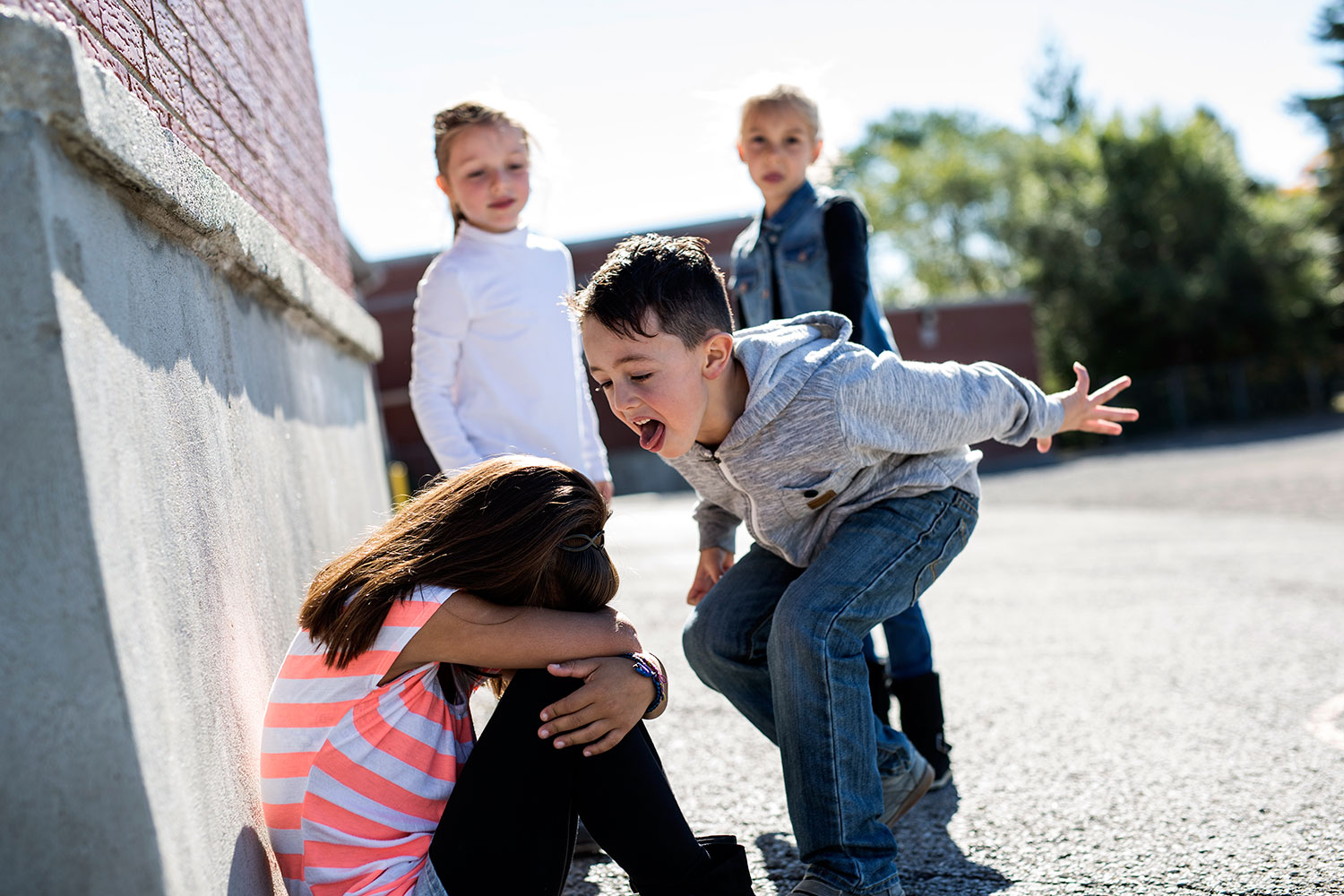 un niño se burla de una niña en el patio del colegio