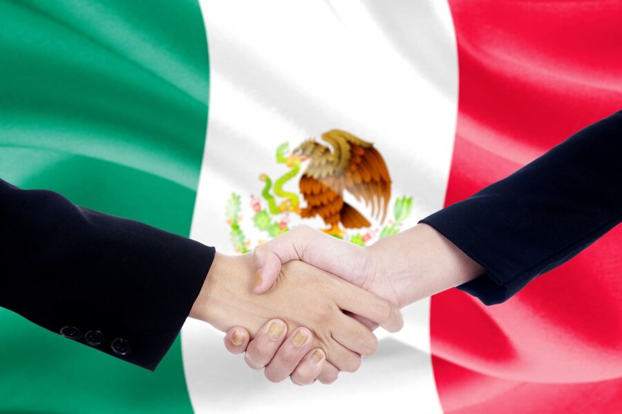 apretón de manos con la bandera de México detrás