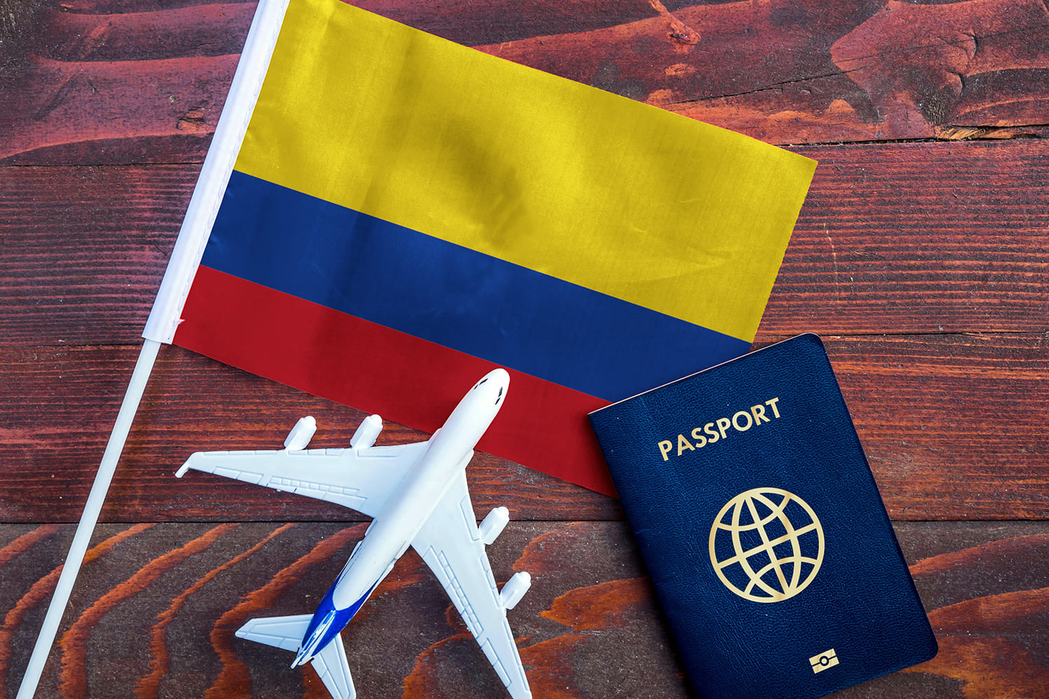 una bandera de Colombia, un avión comercial de pasajeros y un pasaporte