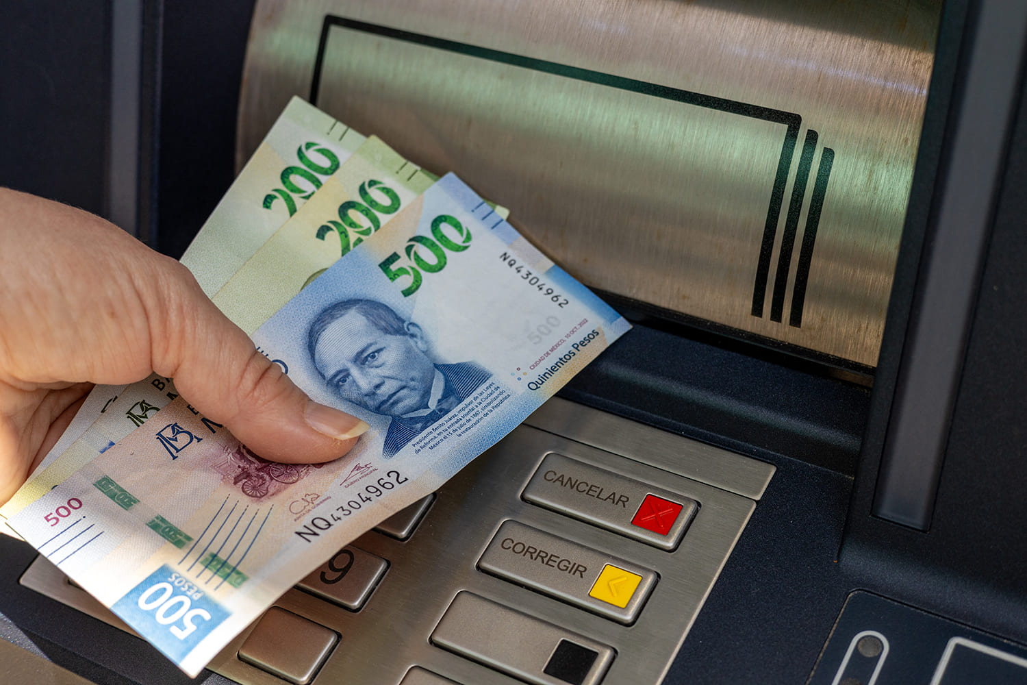 una mujer retira pesos mexicanos de un cajero automático