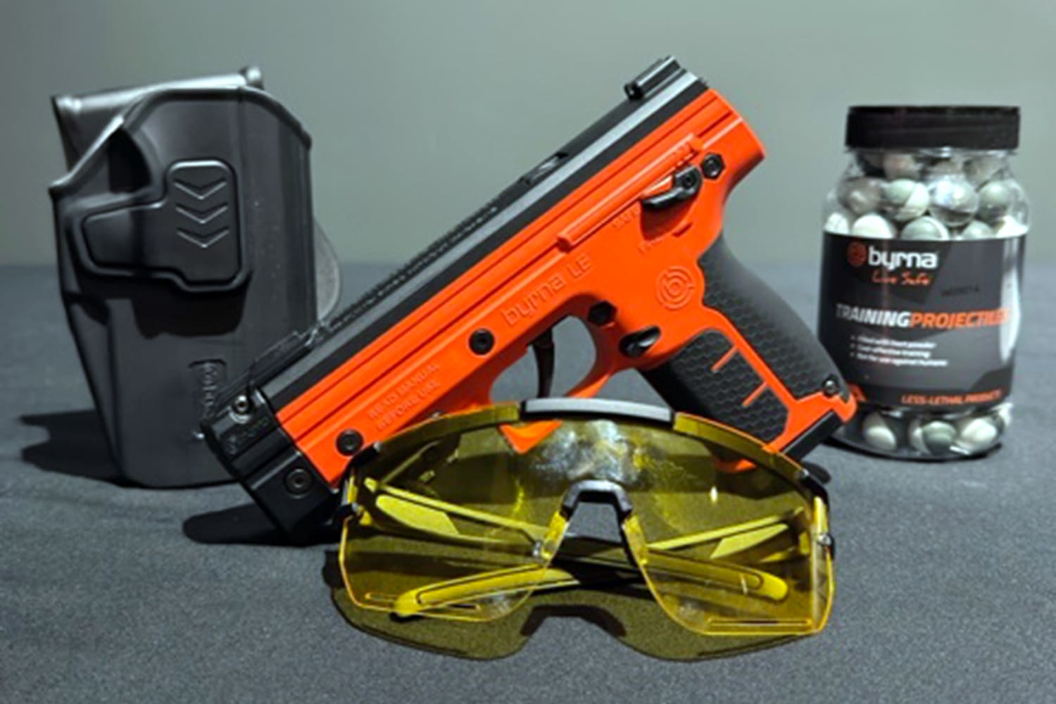 una pistola e la marca Byrna junto a proyectiles y unas gafas de protección