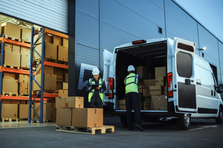 un hombre carga un furgón de mercancías mientras una operaria controla el contenido de un pallet