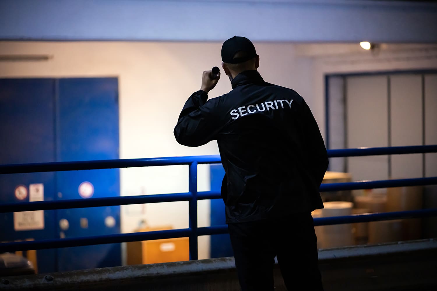 un guardia de seguridad privada ilumina un almacén con una linterna durante un rondín nocturno